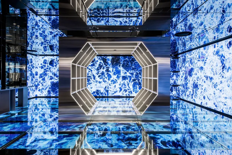 Upward view through octagonal atrium with illuminated frame and blue patterned wall panels