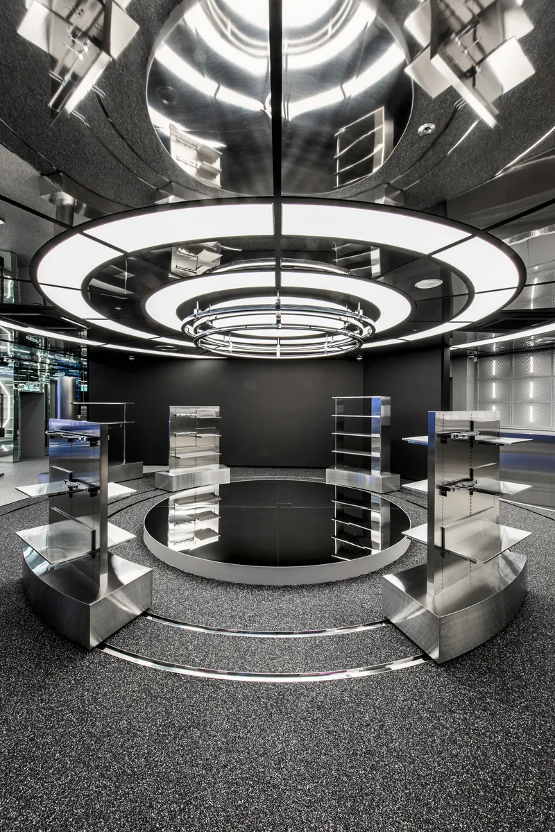 Retail interior with concentric circular ceiling rings reflected in black polished floor and mirrored surfaces