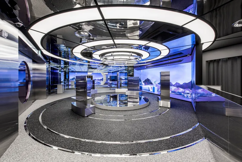 Circular stepped floor under concentric ring light fixtures with blue projected landscape imagery on surrounding walls