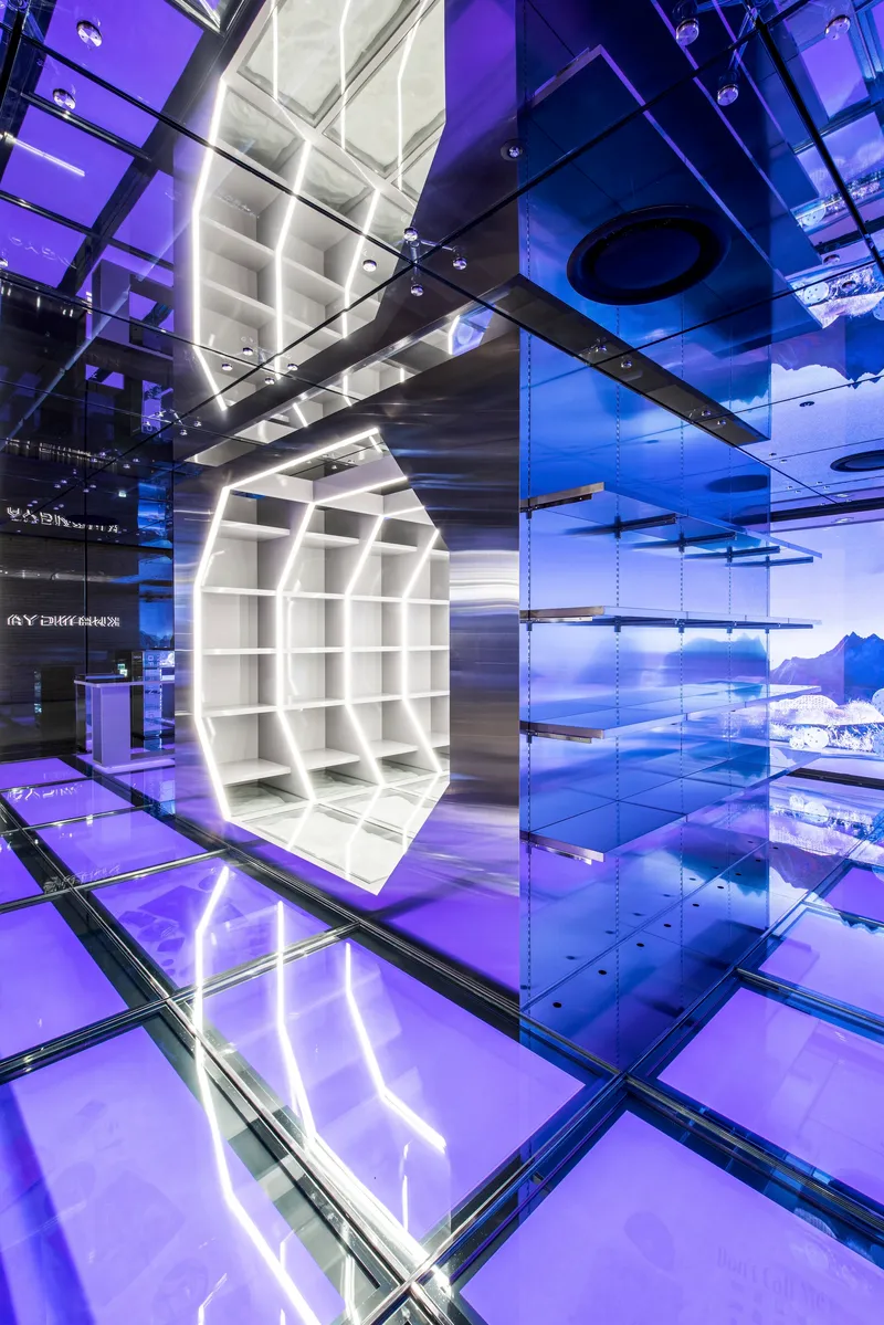 White shelving cube suspended in atrium space with transparent glass floor and blue lit walls