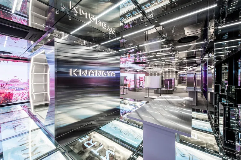 Polished stainless steel reception desk beneath reflective ceiling panels and linear lighting strips