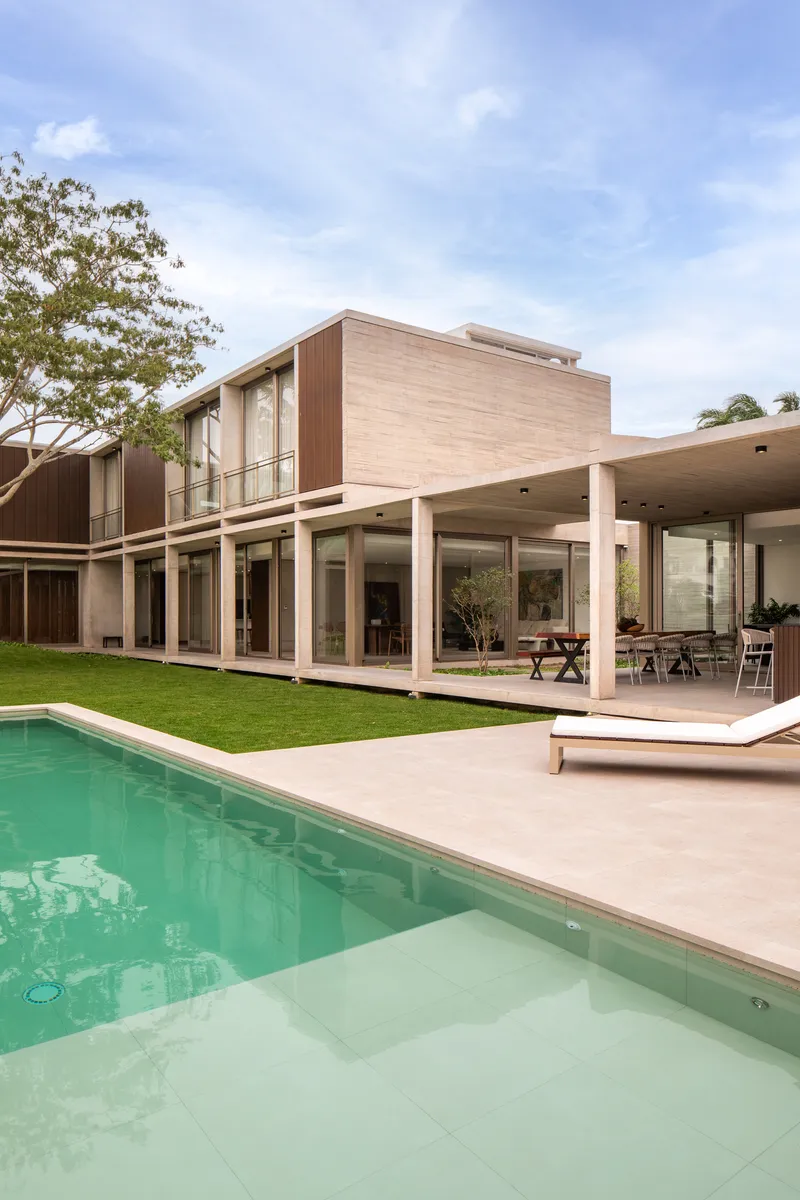 Rear elevation with pool, covered terrace with columns, and timber-clad upper volume framing the lawn