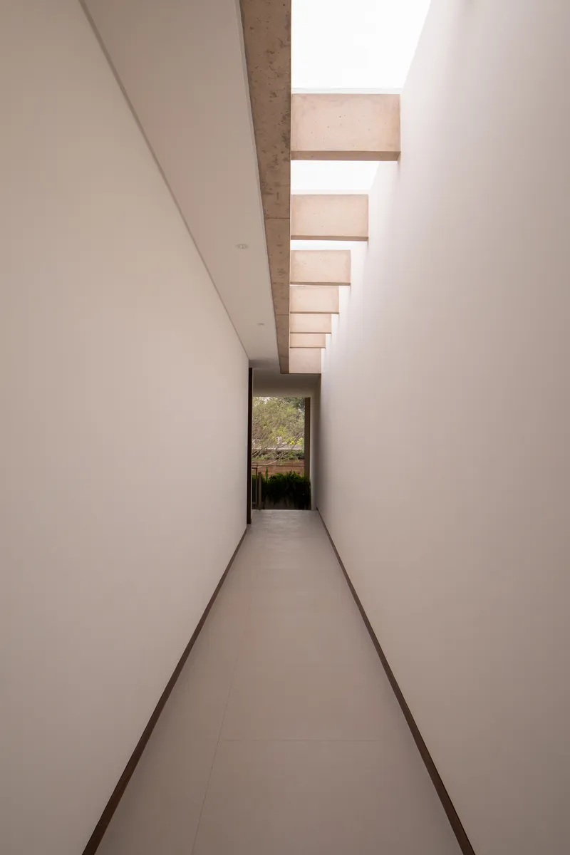 Narrow corridor with clerestory skylight slots and a view through to the garden