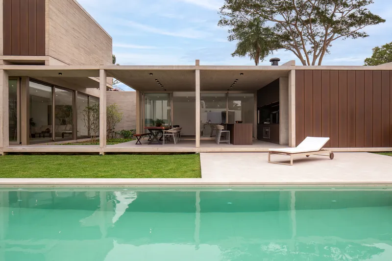 Rear facade with covered terrace and swimming pool framed by lawn and mature trees