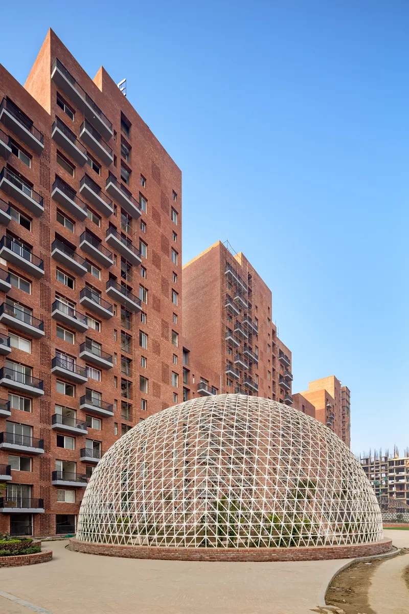 White geodesic dome structure in a courtyard framed by the brick residential towers