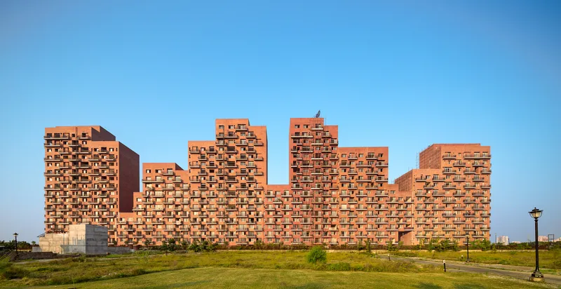 Long view of the zigzagging brick facade with staggered volumes against a bright blue sky