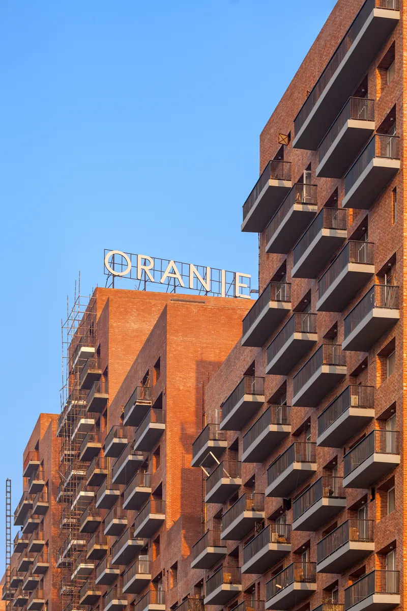 Staggered balconies of brick residential tower with rooftop signage at sunset