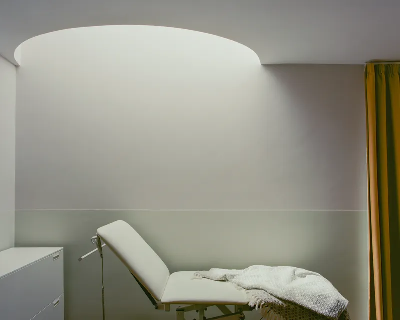 Interior treatment room with curved white ceiling and reclined chair beneath soft ambient light