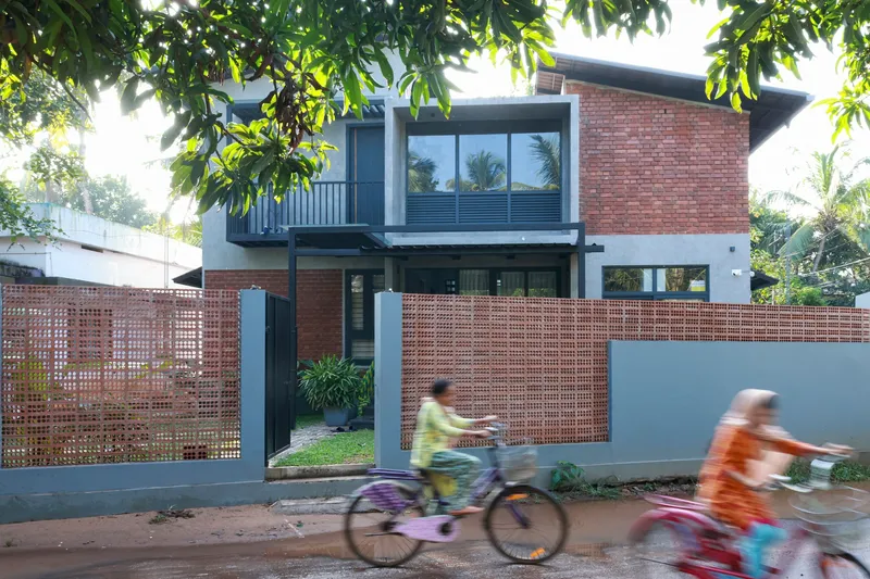 Street view of perforated brick screen wall and facade with cyclists passing in motion blur