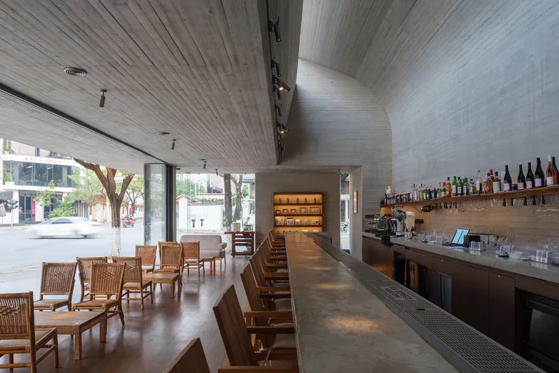 Interior cafe space with board-formed concrete vault ceiling and long counter with wooden stools