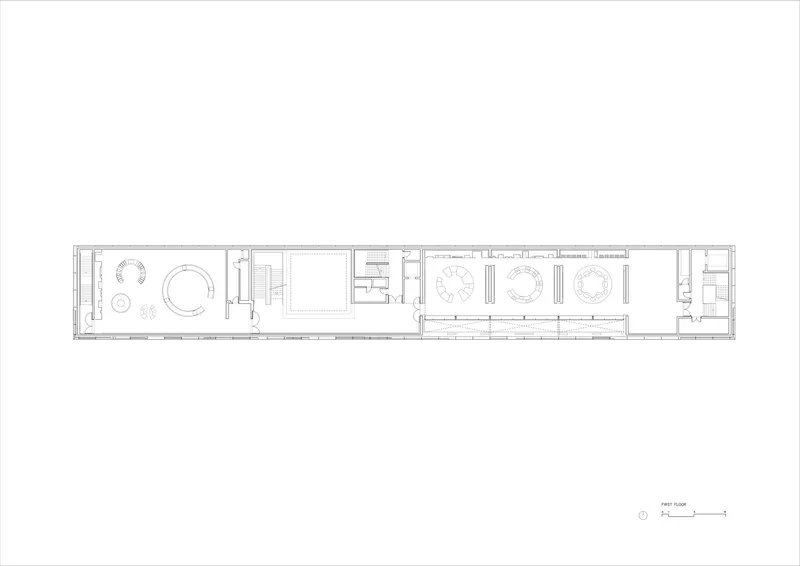 Floor plan drawing showing a long narrow volume with circular meeting spaces and rows of workstations