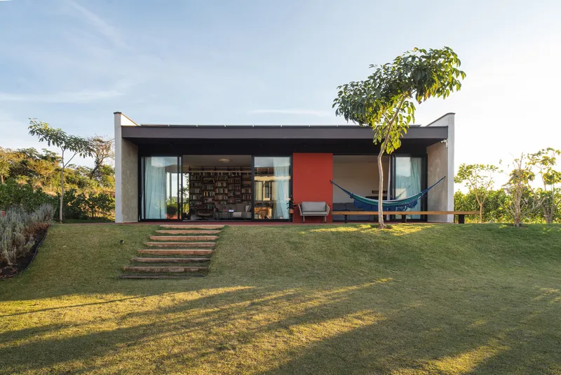 Garden facade with concrete butterfly roof and glazed walls framing interior views at dusk