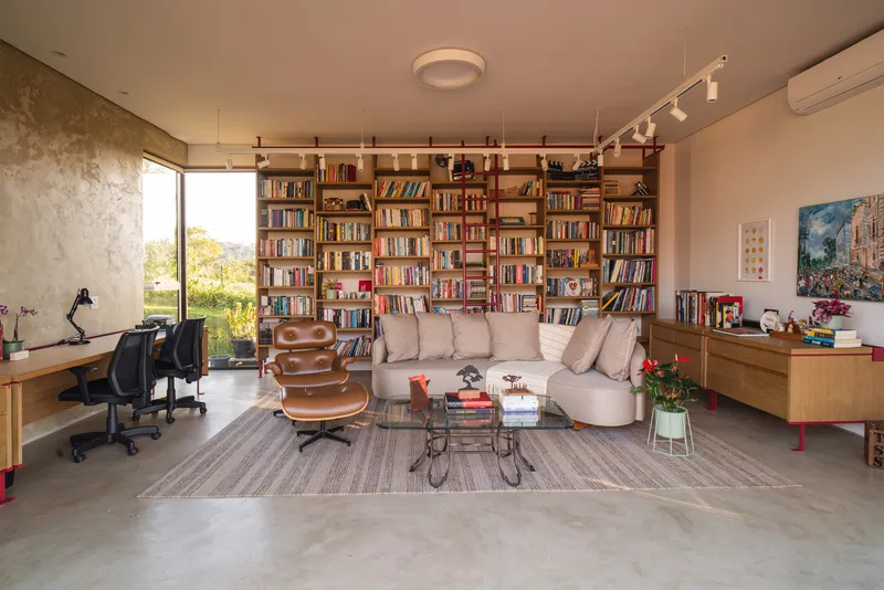 Living room with floor-to-ceiling bookshelf and polished concrete floor under track lighting