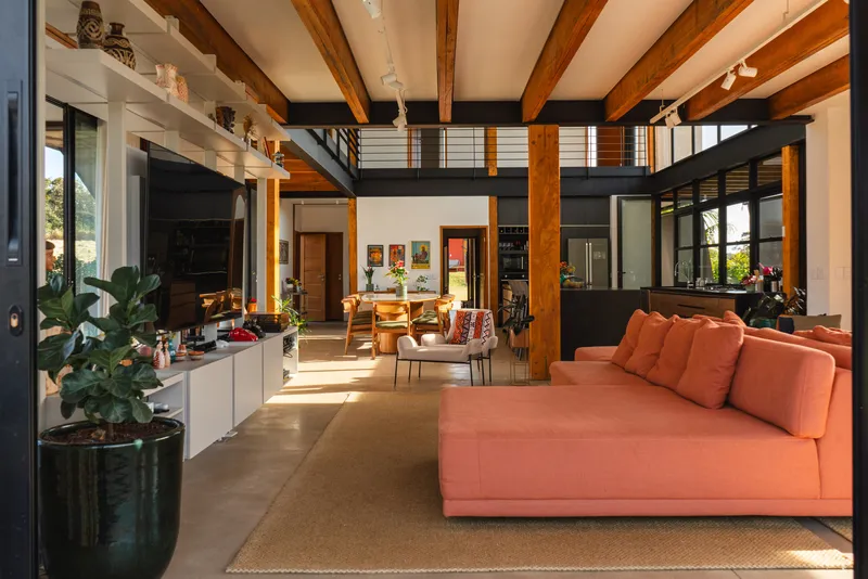 Interior showing double-height space with timber columns and black steel mezzanine in afternoon sun