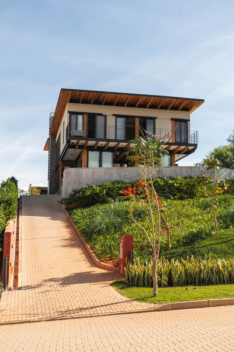 Two-story residence with cantilevered timber roof and horizontal railings above landscaped sloping entry path