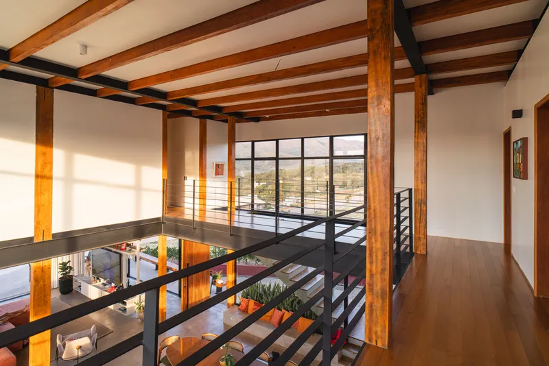 Second floor walkway with black steel railings and timber columns overlooking the double-height space below