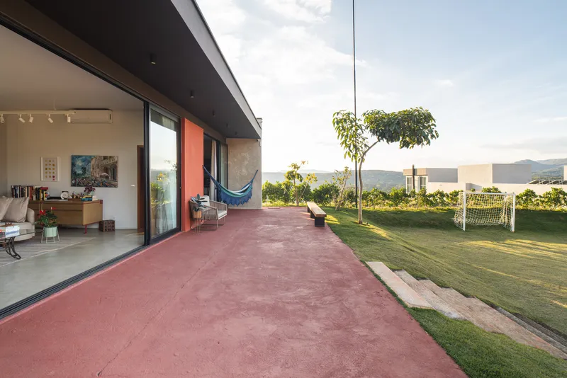 Covered terrace with red concrete paving adjacent to lawn with a soccer goal and distant hills