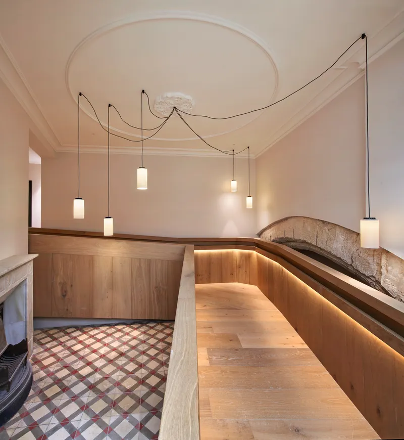 Curved timber bench with integrated lighting below pendant fixtures and a circular ceiling medallion