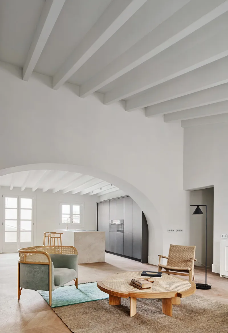 Living room with white beamed ceiling, arched doorway, and timber furniture on a woven rug