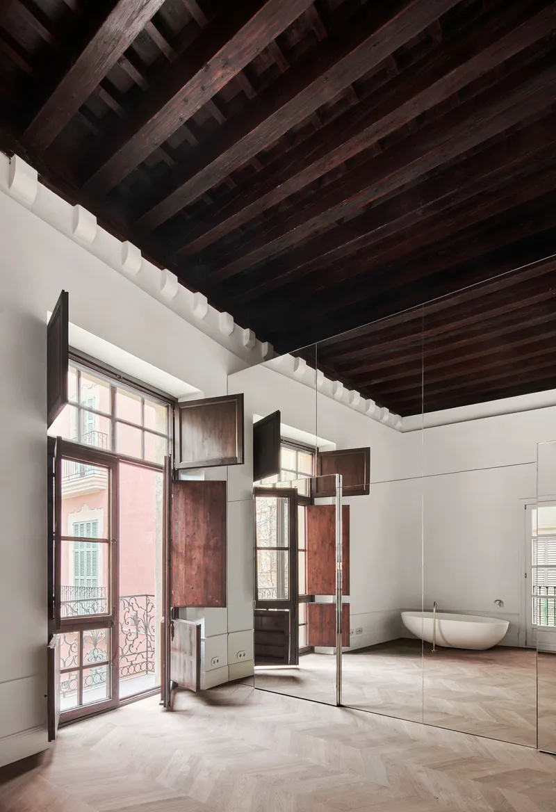 Bathroom with herringbone floor, mirrored walls, dark timber ceiling beams, and open timber shutters