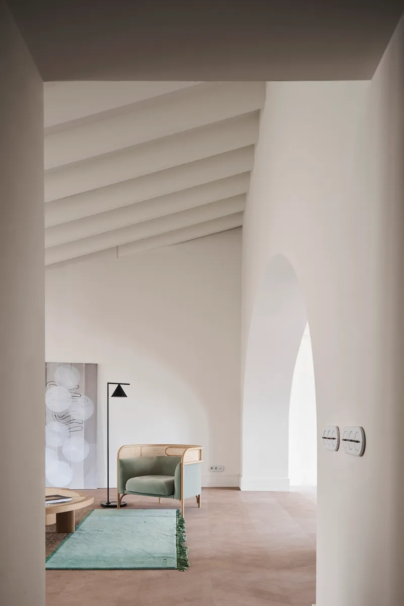 View through arched opening into a double-height space with ribbed vaulted ceiling and pale plaster walls