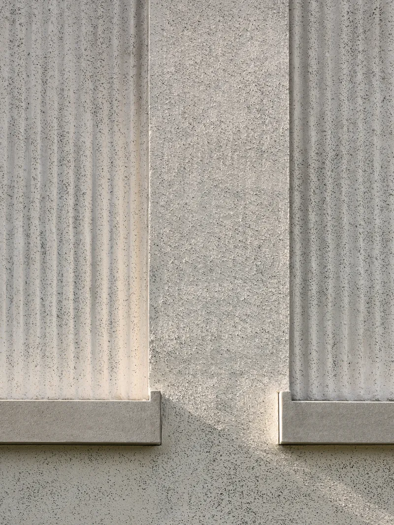 Close-up of vertically fluted concrete panels meeting at a corner joint in bright sunlight