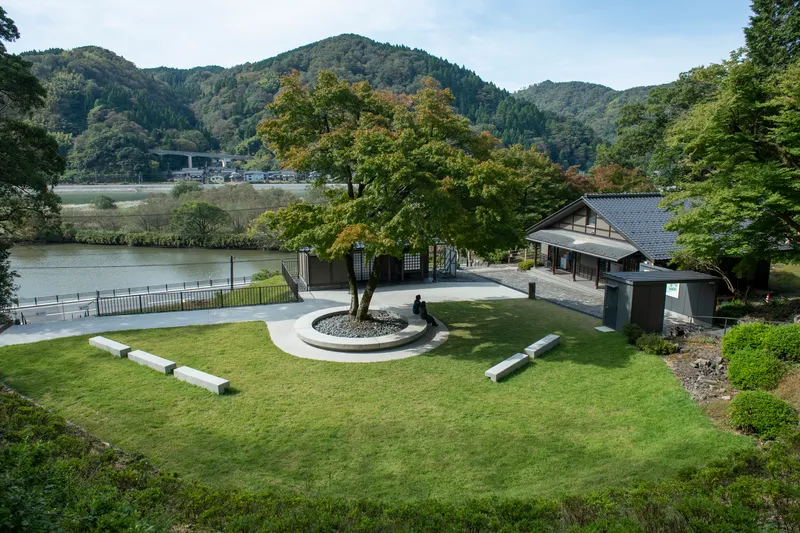 Overview of the lawn with circular tree planting and concrete benches overlooking a river valley