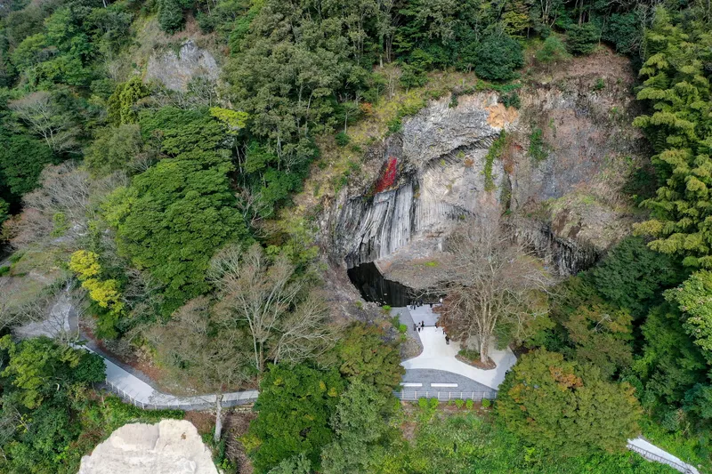 Drone view of the pathway approach to a cave entrance within a forested hillside