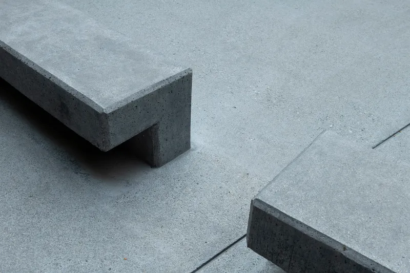Detail of concrete bench corner casting shadow on poured concrete plaza surface