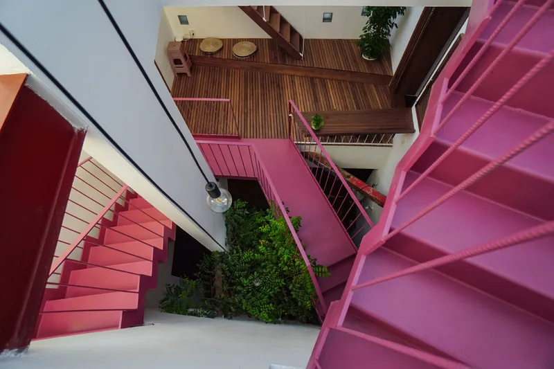 Aerial view of pink steel staircases wrapping around a planted courtyard with timber flooring above