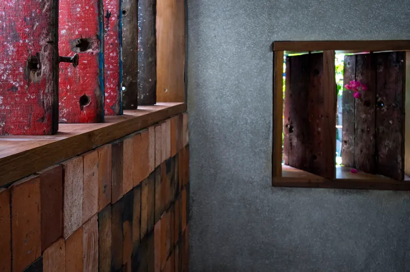 Interior counter with reclaimed timber cladding next to framed window opening in concrete wall