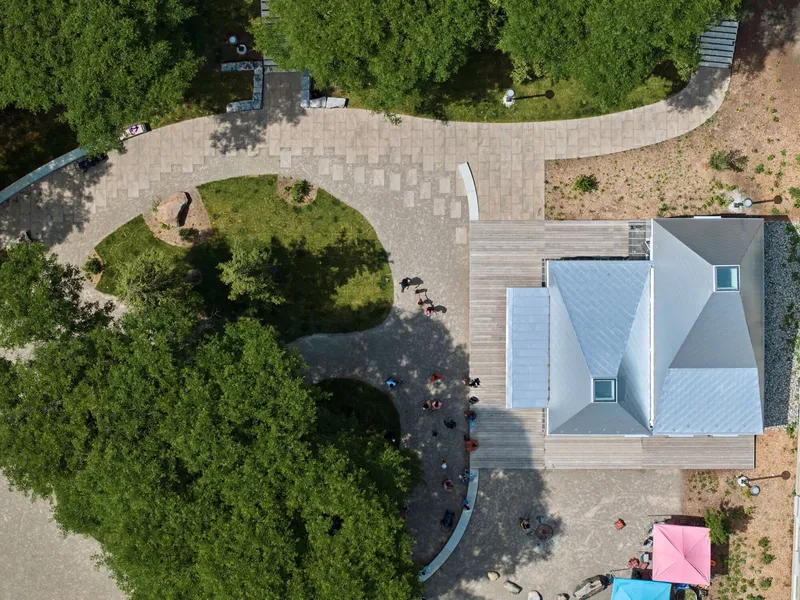 Aerial view of the pyramidal gray roof among wooden decking and dense tree canopy