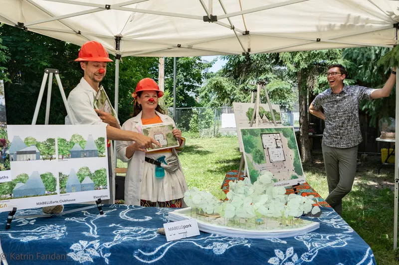 Site model and renderings displayed on table under white tent canopy during community engagement event