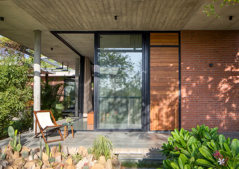 Covered porch with board-formed concrete ceiling and sliding glass doors flanked by cacti and succulents