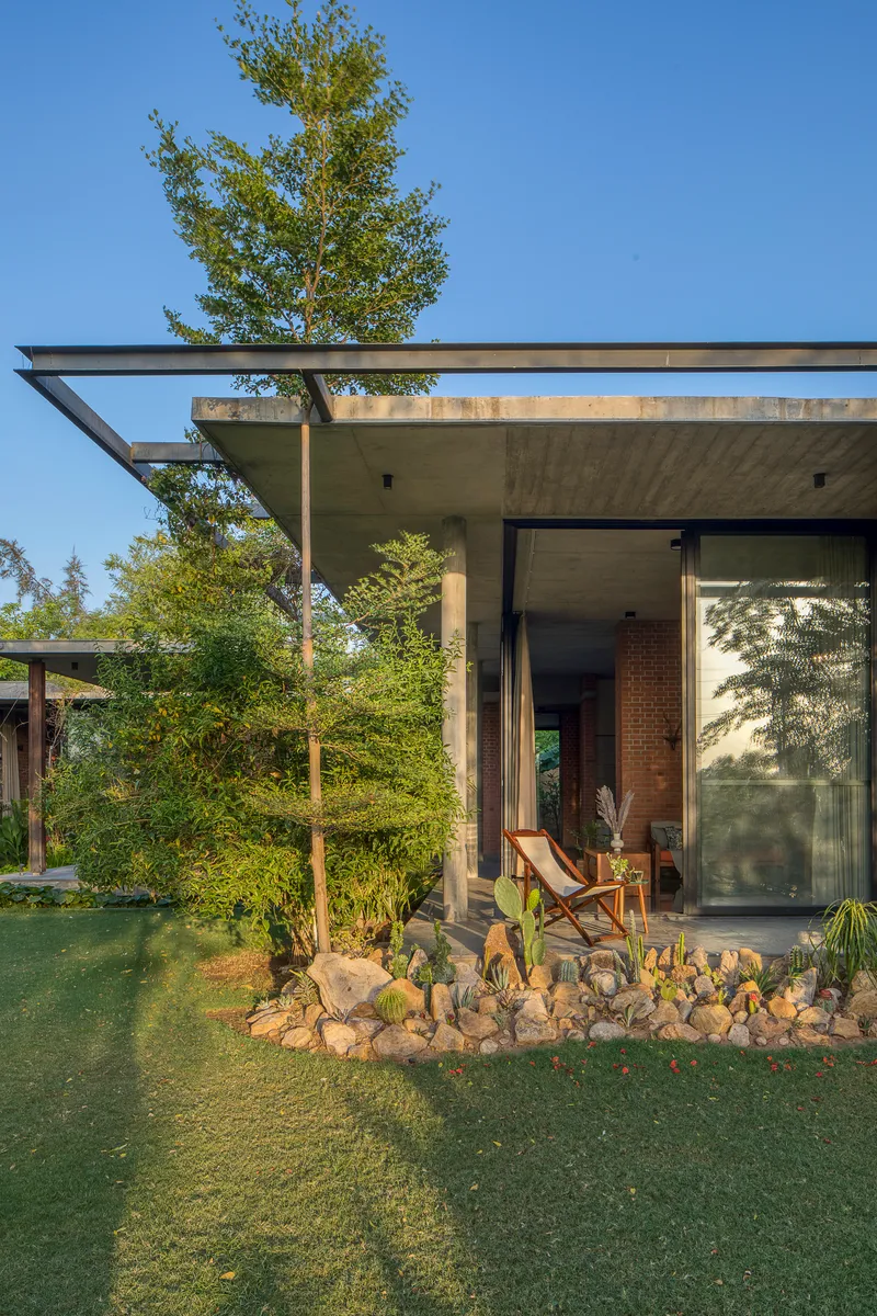 Cantilevered concrete roof overhang above the glazed entrance with cacti and rock garden in foreground