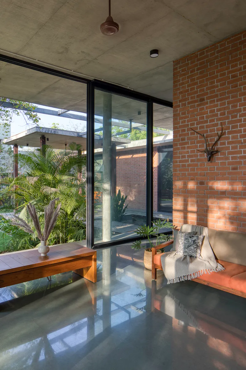Interior living space with polished concrete floor reflecting light from glazed walls overlooking planted courtyard