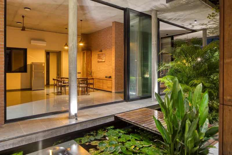 Interior courtyard with lily pond and sliding glass doors opening to dining area under concrete ceiling