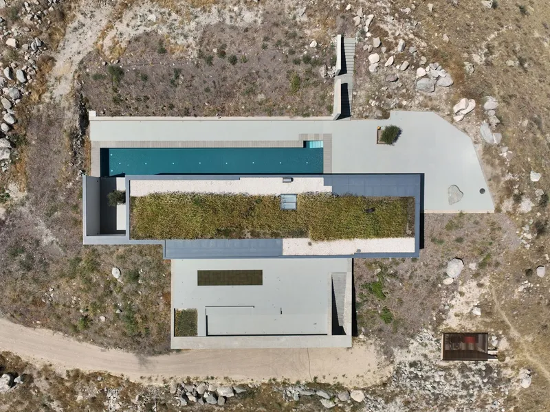 Aerial view showing flat roof composition with courtyard garden and pool set in rocky terrain