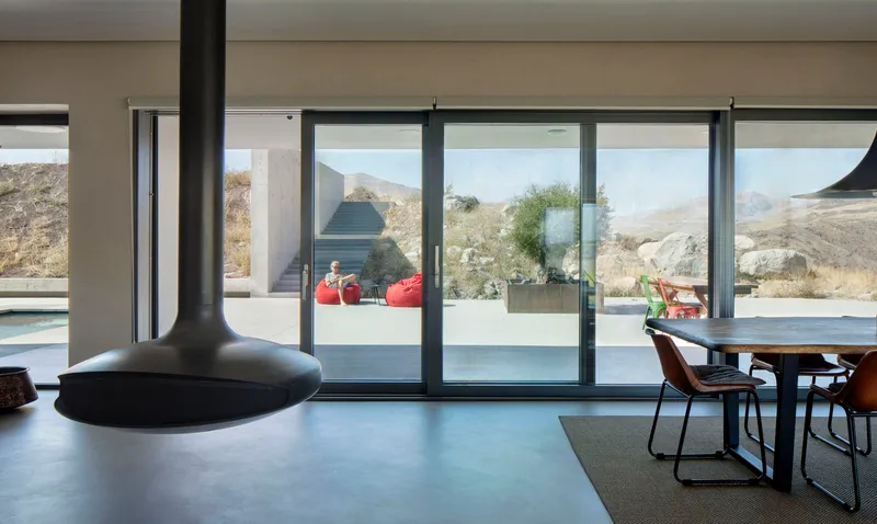 Interior living space with pendant fireplace and sliding glass doors opening to a terrace with mountain views