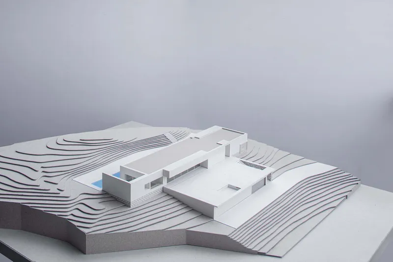 Physical model showing terraced site contours surrounding a flat-roofed residence with pool courtyard