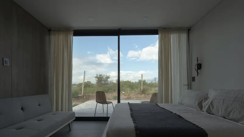 Bedroom interior with full-height glazing framing a view of the desert landscape