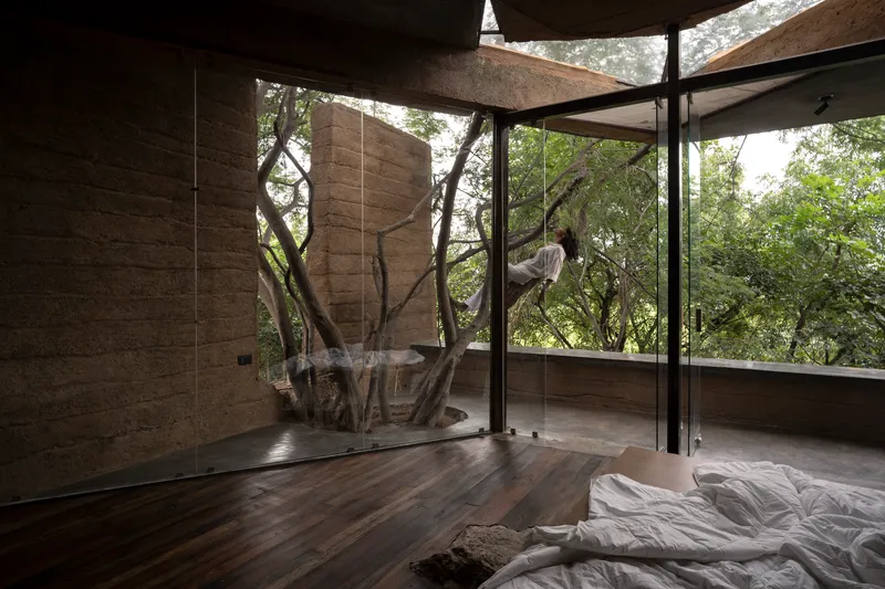 Bedroom with preserved tree trunk penetrating through timber floor and glass enclosure