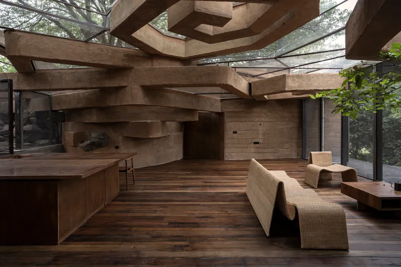 Interior showing the sculptural rammed earth ceiling planes above timber floors and woven furniture