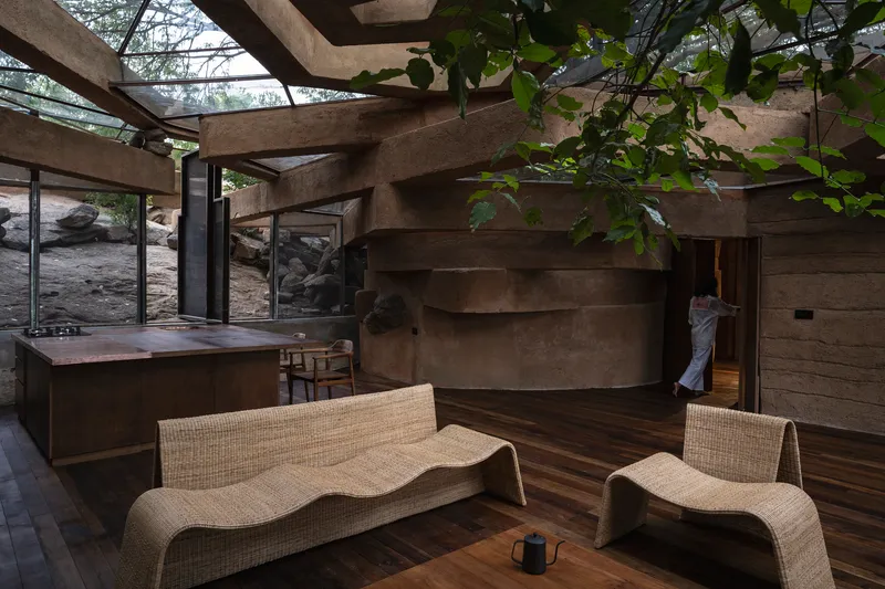 Stepped concrete wall wrapping the interior with exposed roof beams and partial glass ceiling