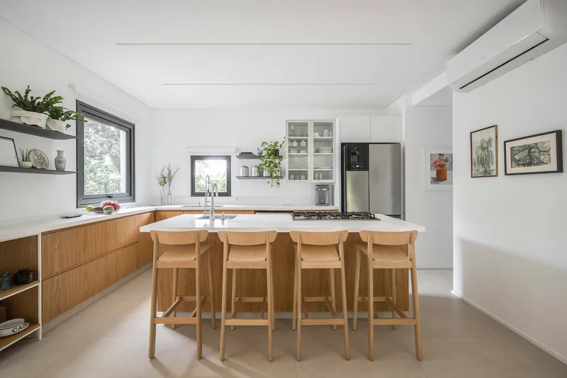 Open kitchen with timber cabinetry, island with four bar stools, and white countertops