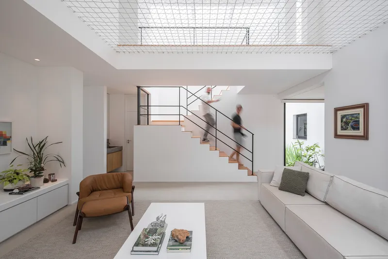 Interior view of white staircase with steel railings and wire mesh ceiling panel above