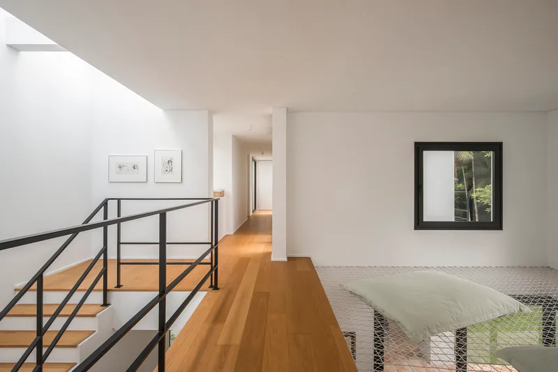 Upper corridor with timber flooring, steel railing overlooking mesh screen, and framed window