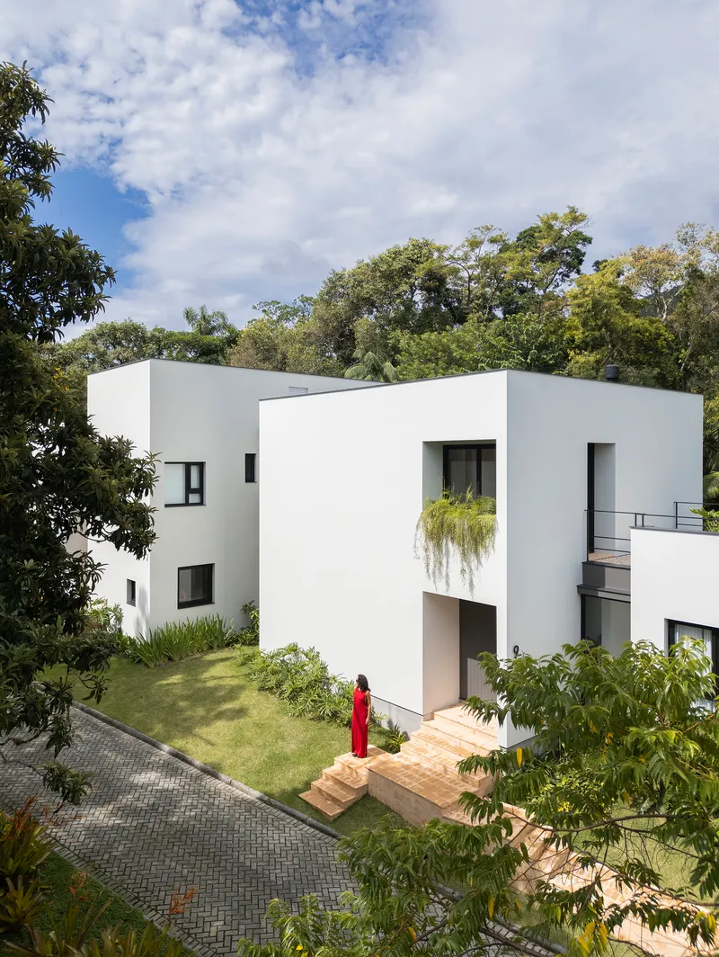 Elevated white facade with recessed entrance and figure in red descending brick steps to lawn