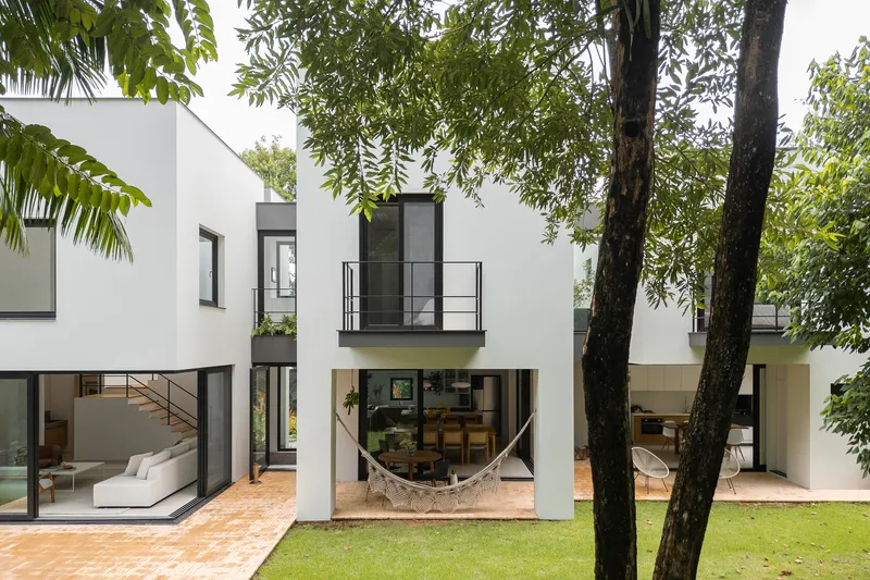 Rear elevation with glazed openings and hammock on terrace between tree trunks and lawn