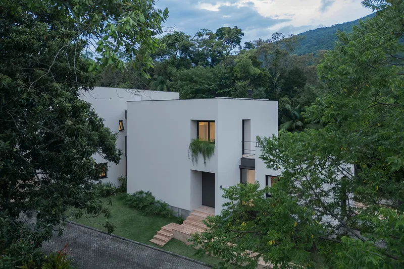White stucco facade with timber entrance steps ascending the lawn under cloudy afternoon light